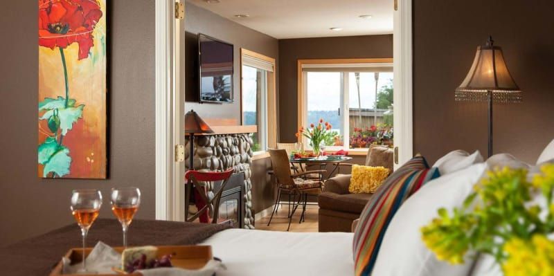 A bedroom with a tray of grapes and wine glasses on the bed.