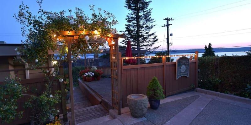 A wooden fence with lights on it is surrounded by trees and bushes.