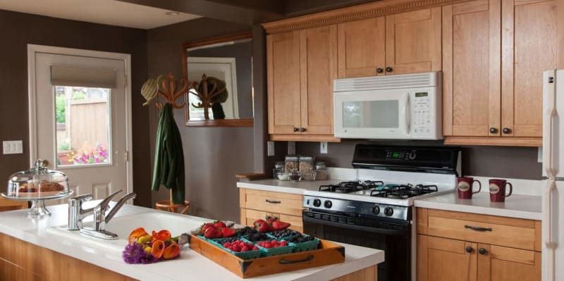 A kitchen with wooden cabinets , a stove , a microwave , a refrigerator and a sink.