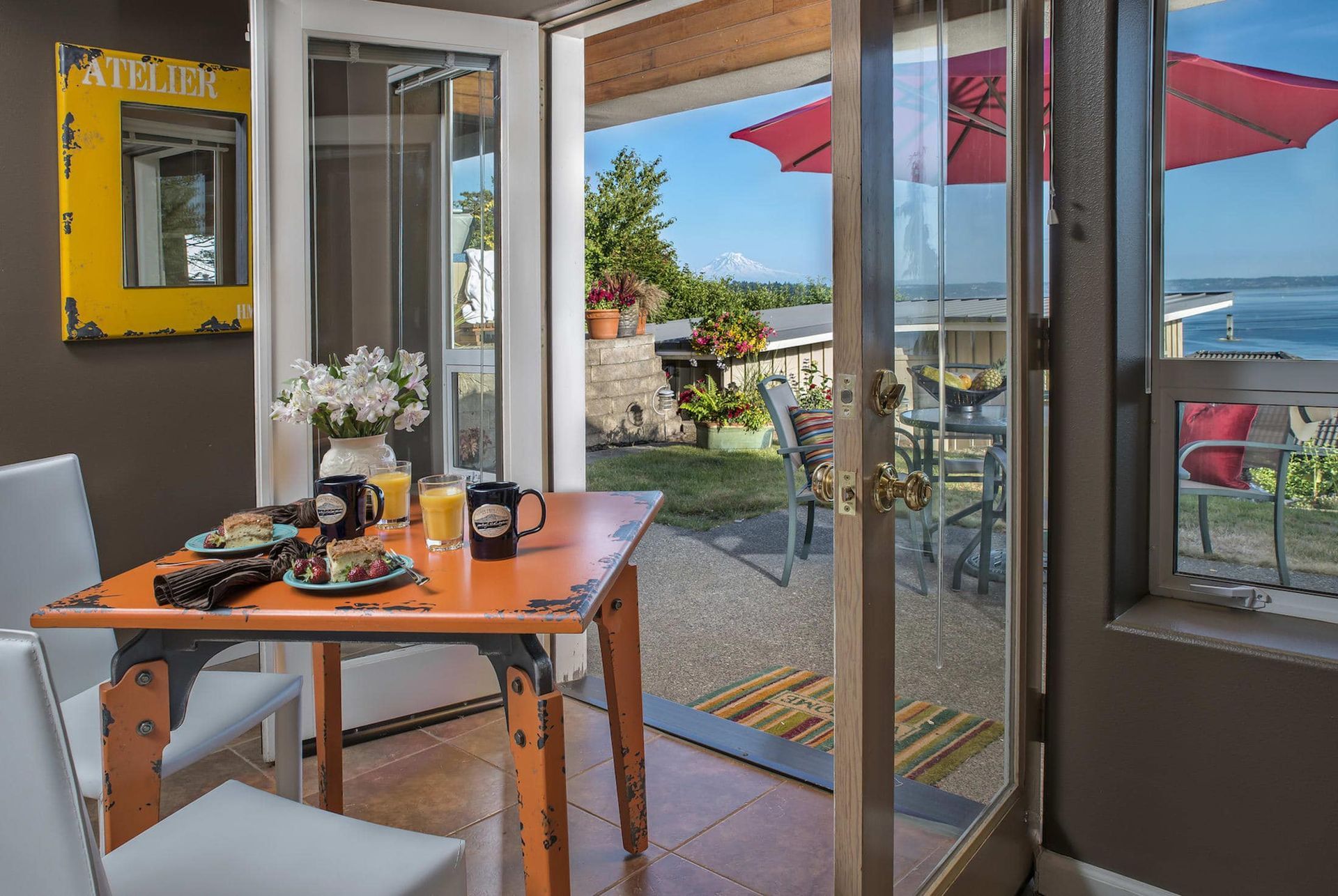 A dining room with a table and chairs and a view of the ocean.