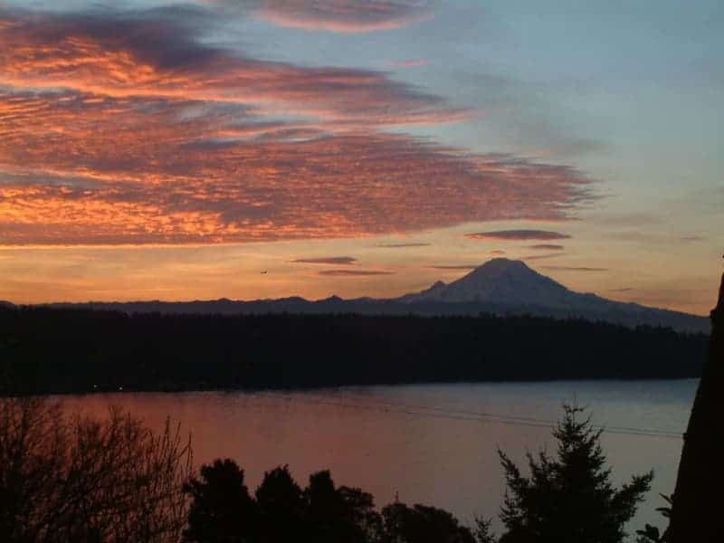 A sunset over a lake with a mountain in the background