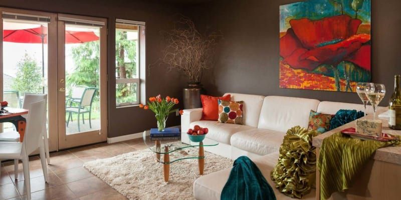 A living room with a white couch and a painting on the wall.