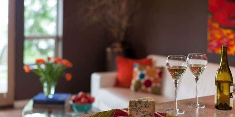 Two glasses of wine and a bottle of wine are on a table in a living room.