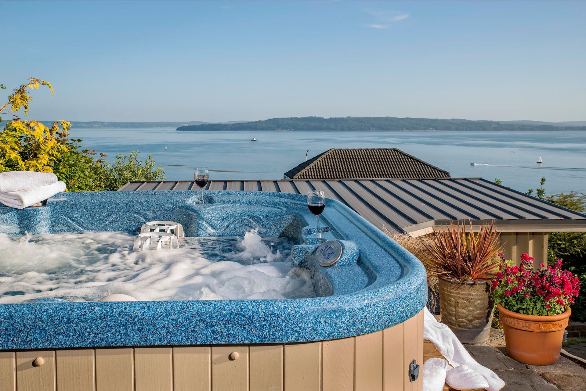 A hot tub with a view of the ocean is on the roof of a house.