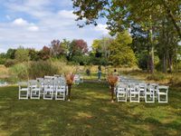 Bride and groom holding hands in a grassy field, the bride’s long veil trailing behind them.