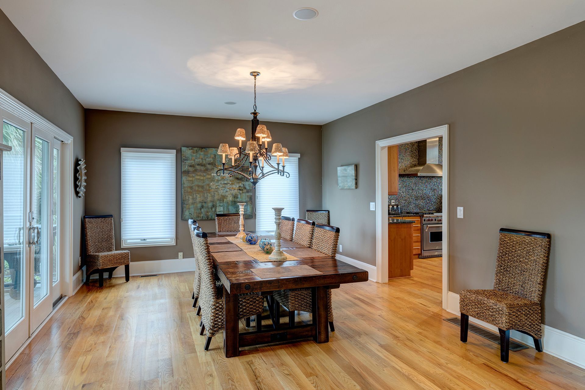 Dining room with wooden table, chairs, hardwood floors, and access to kitchen and outdoors.