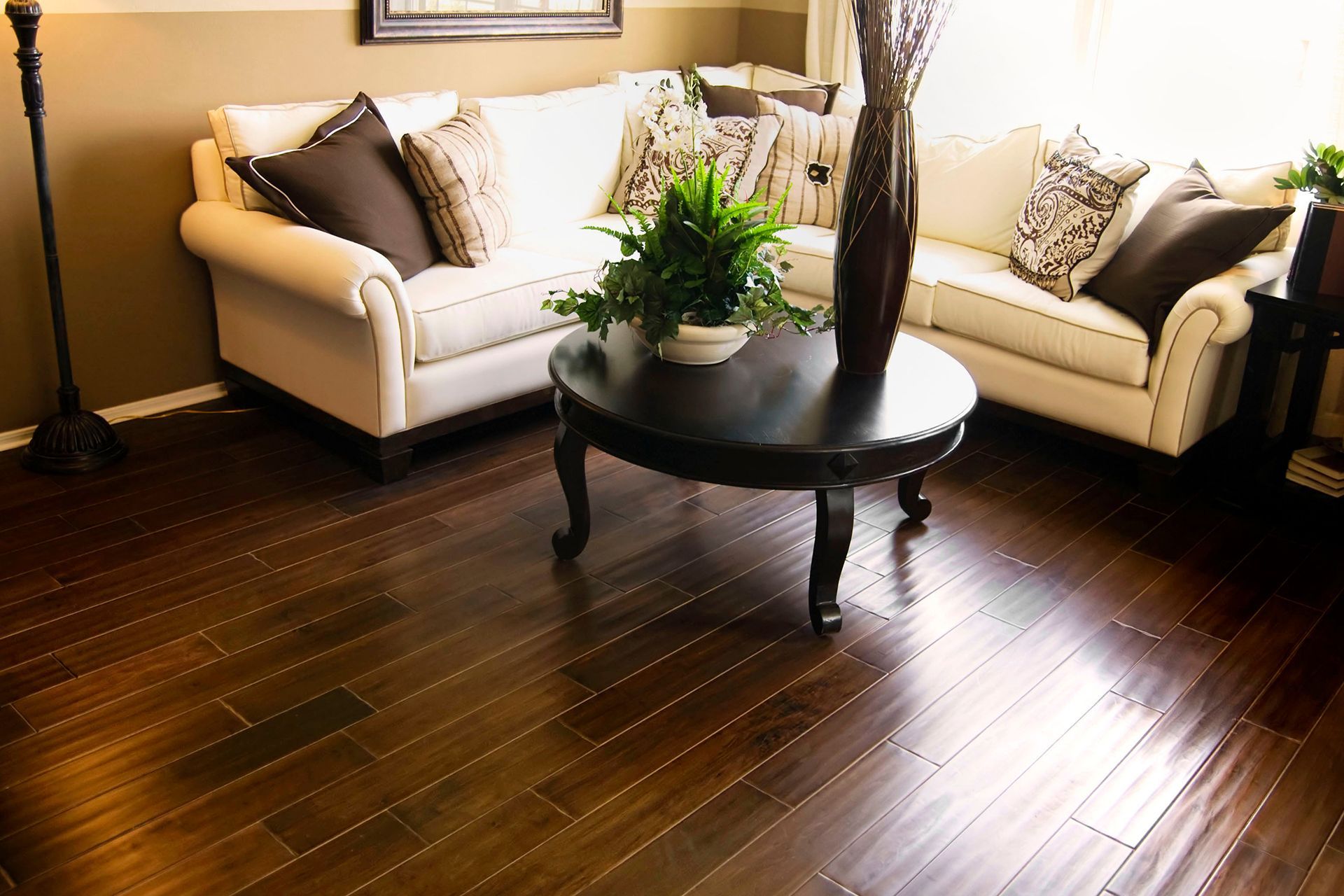 Living room with dark wood floors, white sofa, coffee table, and tall vase.