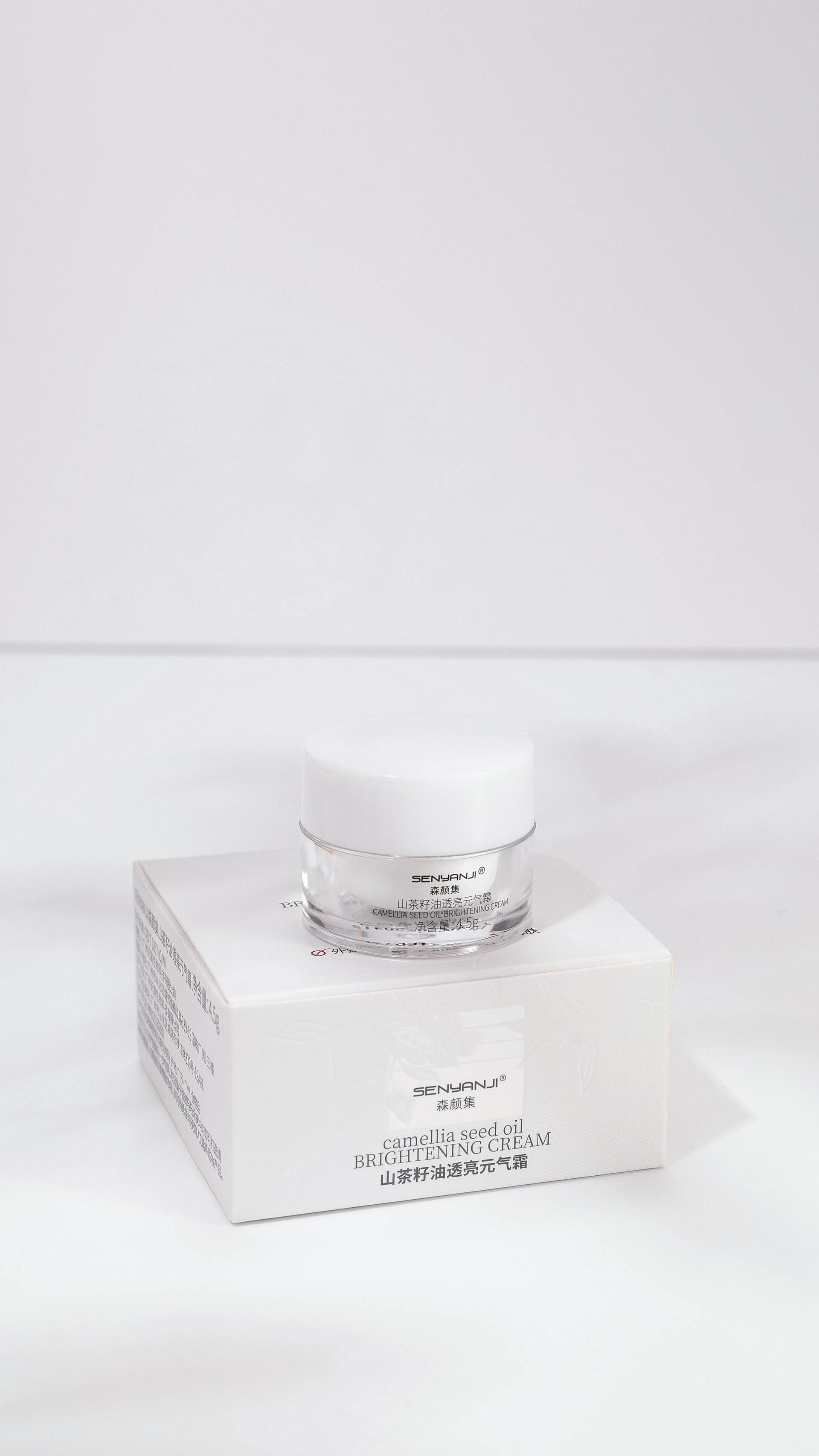 Tarro blanco de producto para el cuidado de la piel encima de una caja blanca sobre un fondo blanco.