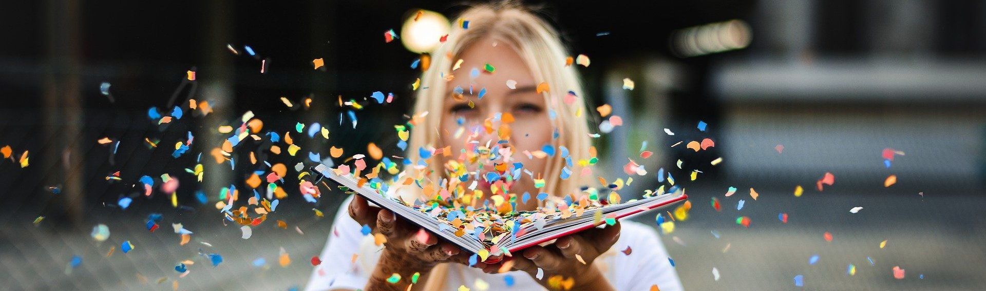 woman blowing confetti from book