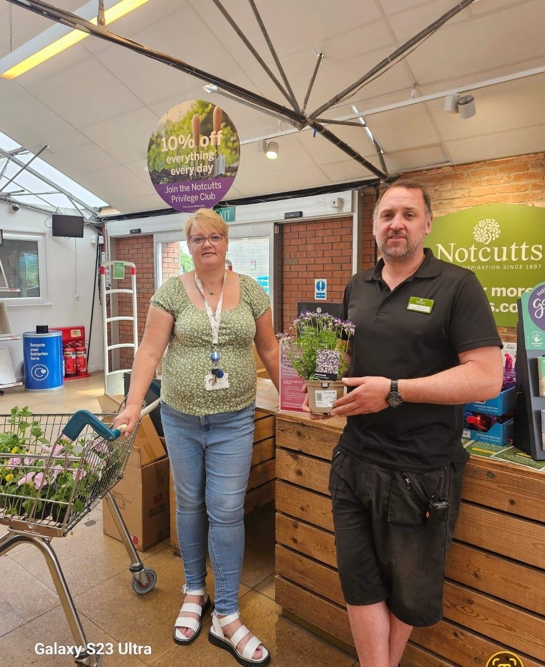 A man and a woman are standing in front of a sign that says 10 % off