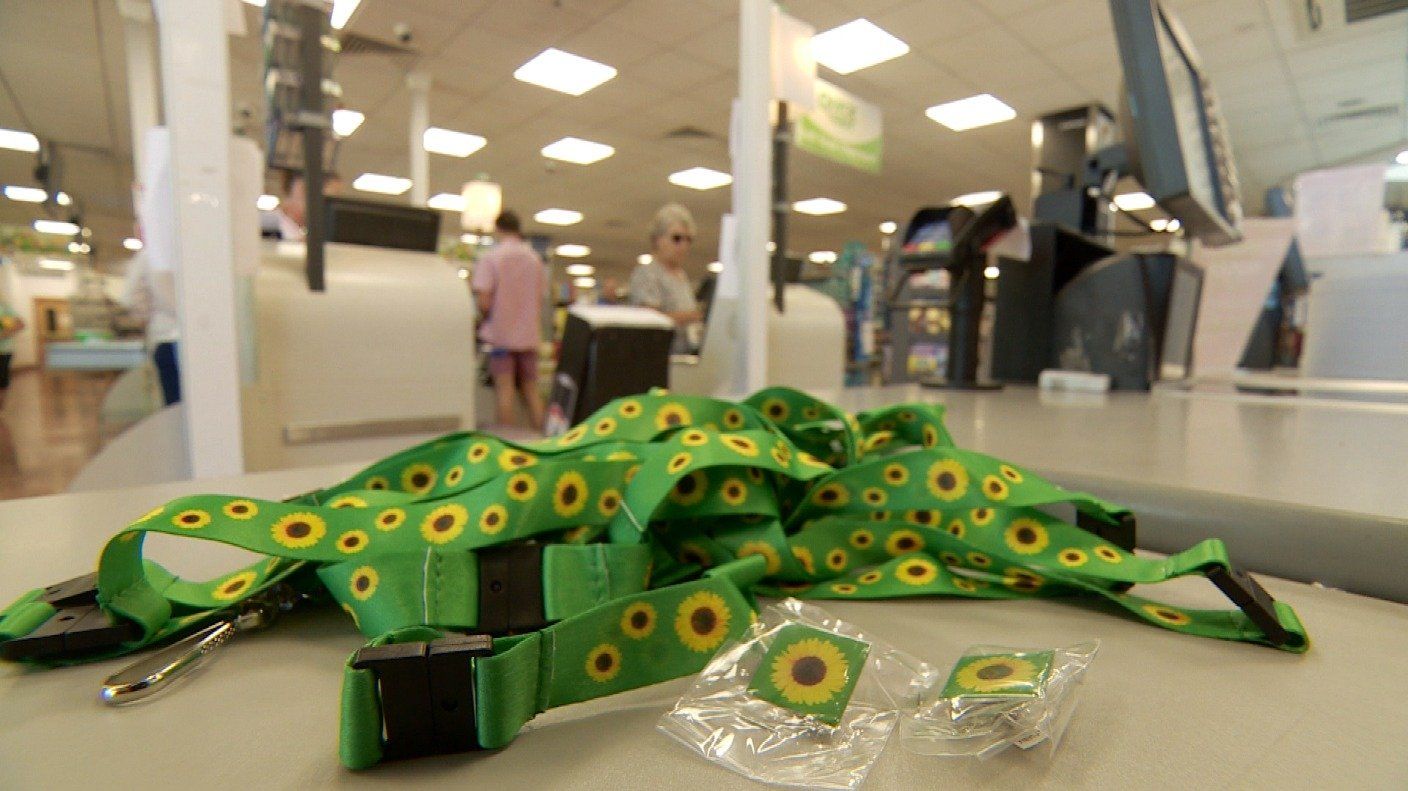 a green lanyard with sunflowers on it is on a table in a store .