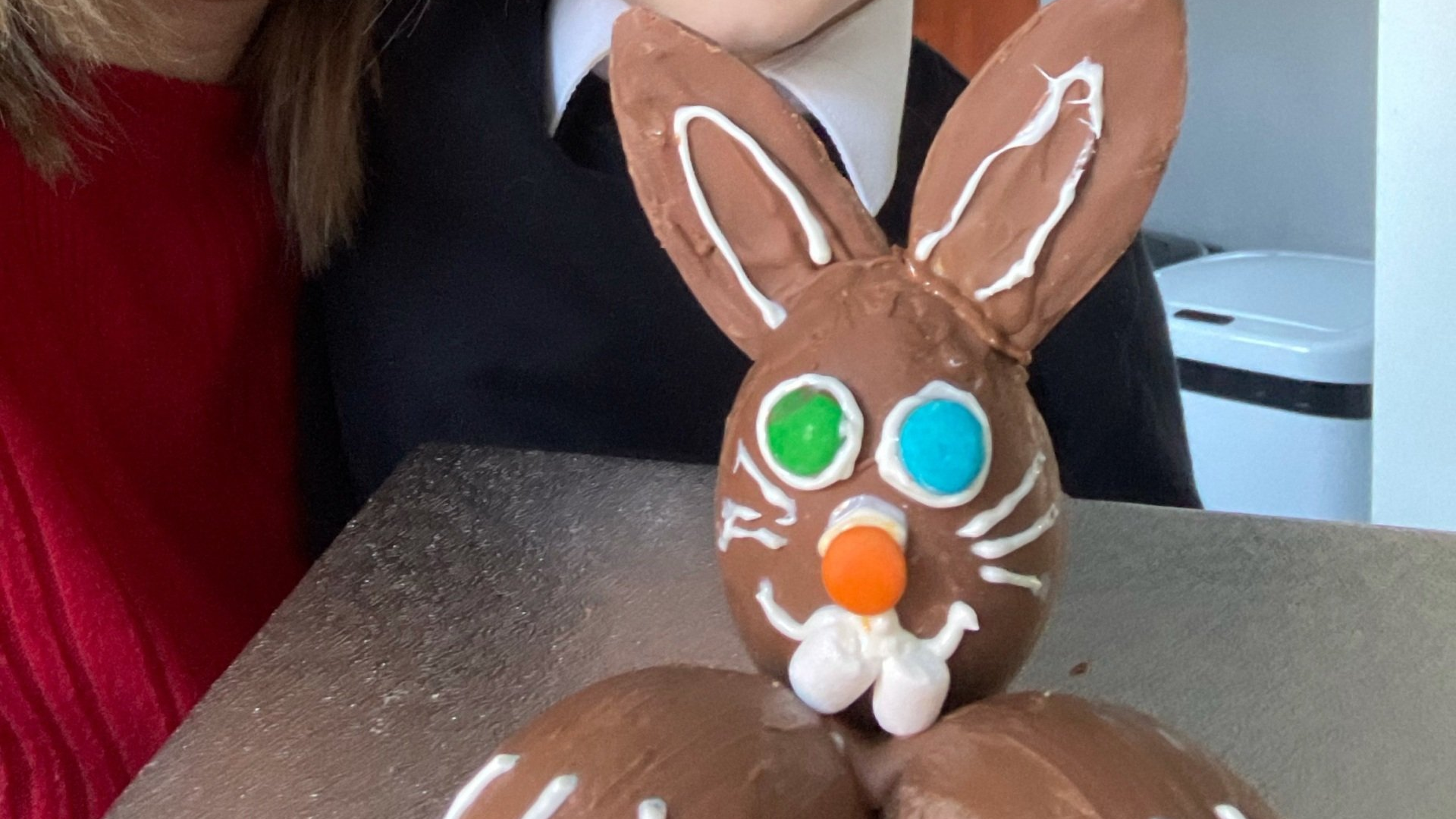 a person is standing next to a chocolate bunny on a table .