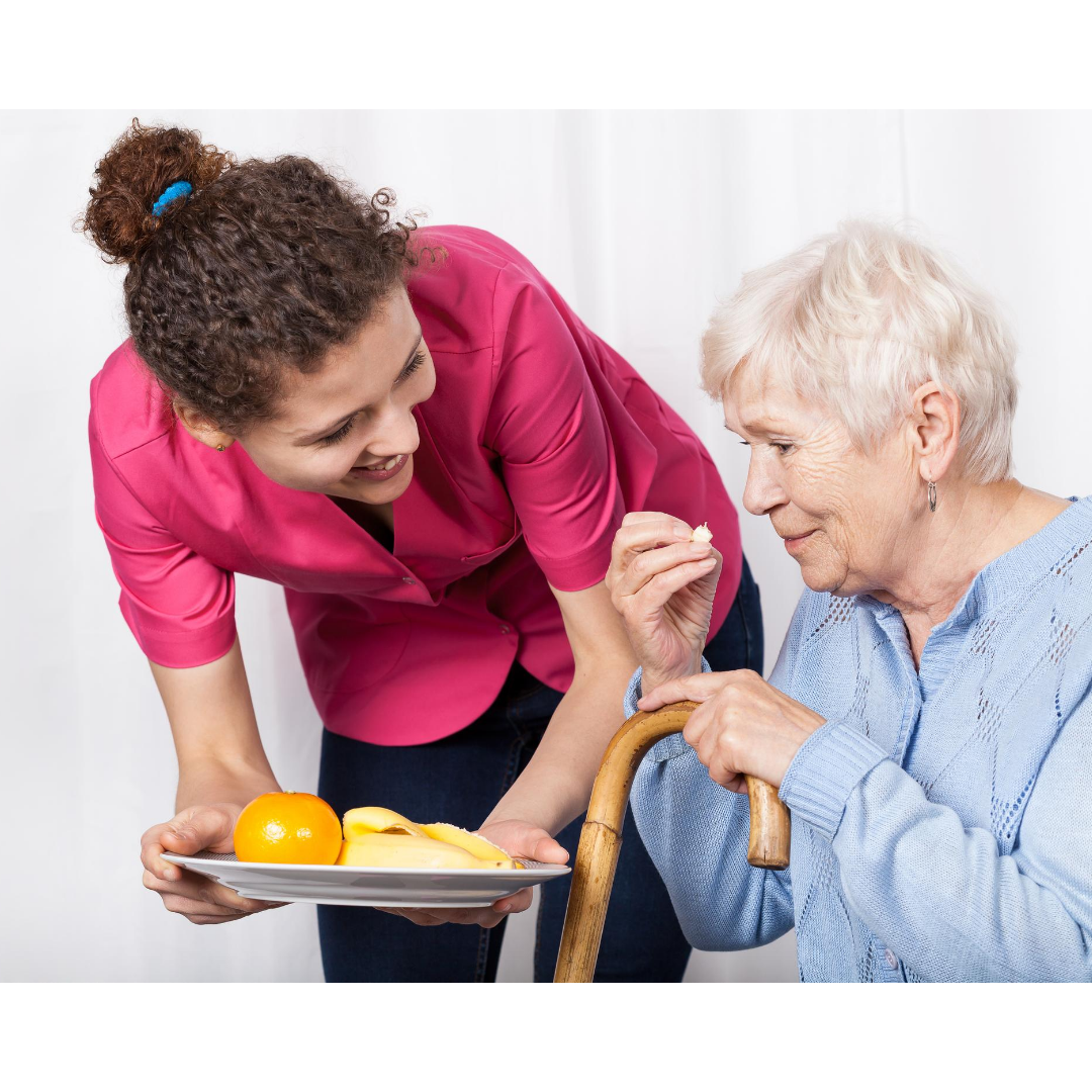 a woman is feeding an elderly woman with a cane a plate of food .