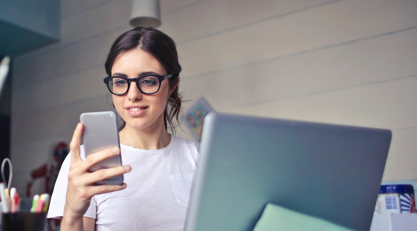 a woman is holding a cell phone in front of a laptop computer .