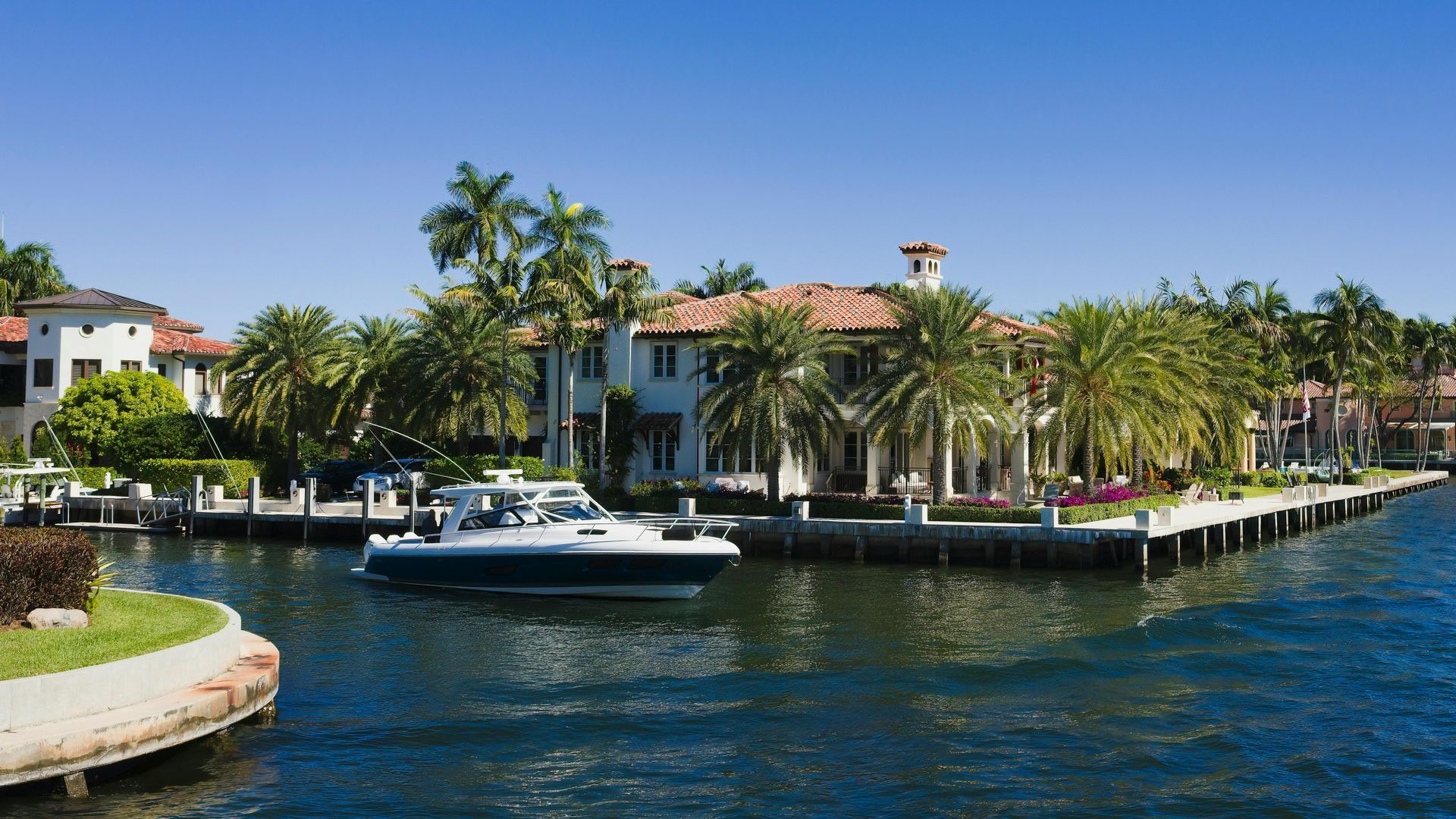 A boat is docked in front of a large house