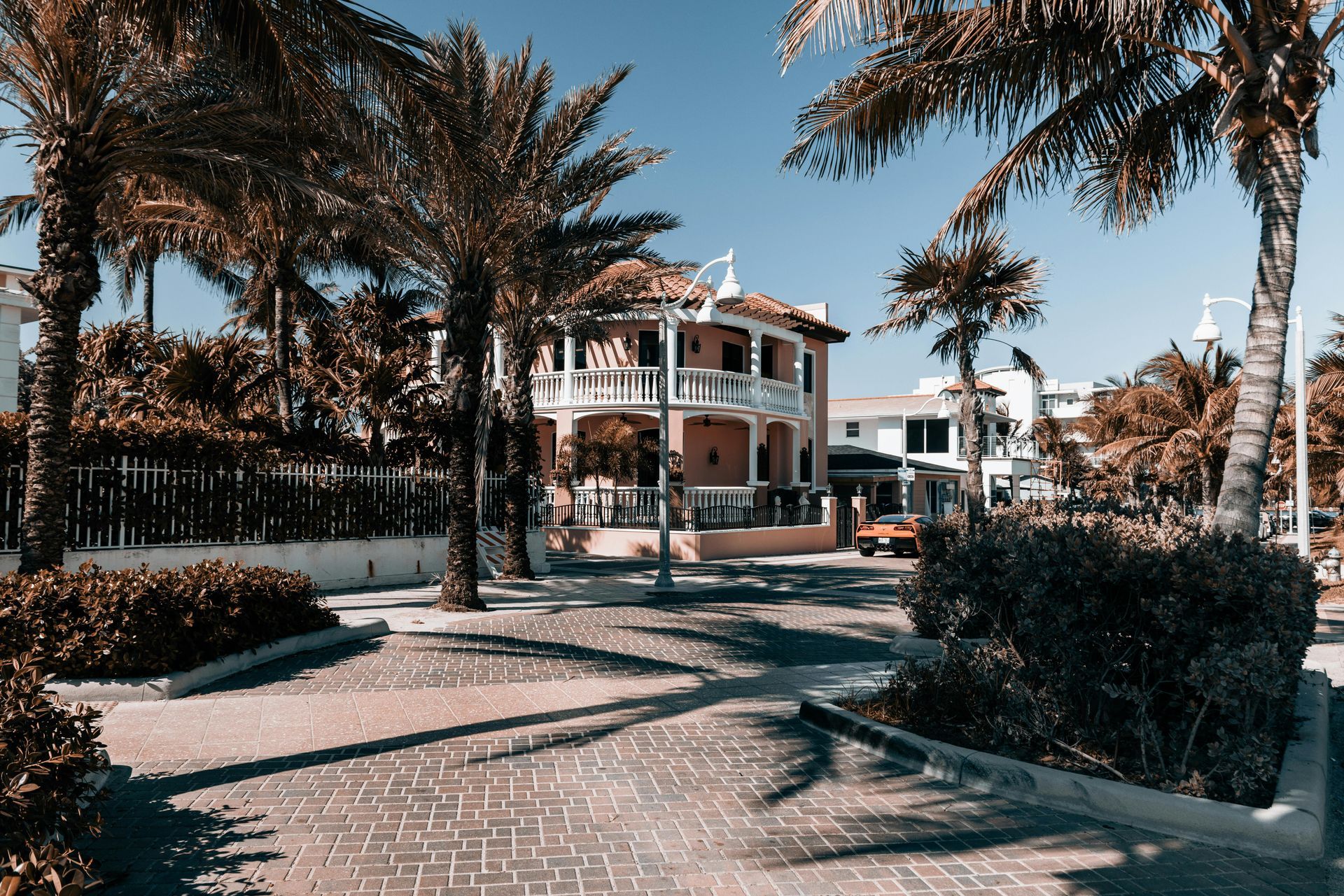 A large house is surrounded by palm trees on a sunny day