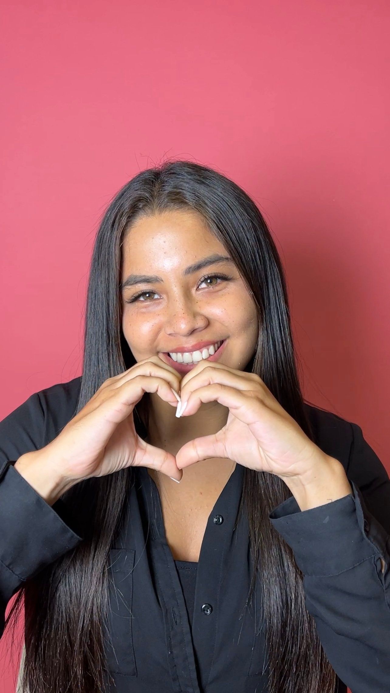 mujer sonriendo haciendo un corazón con sus manos