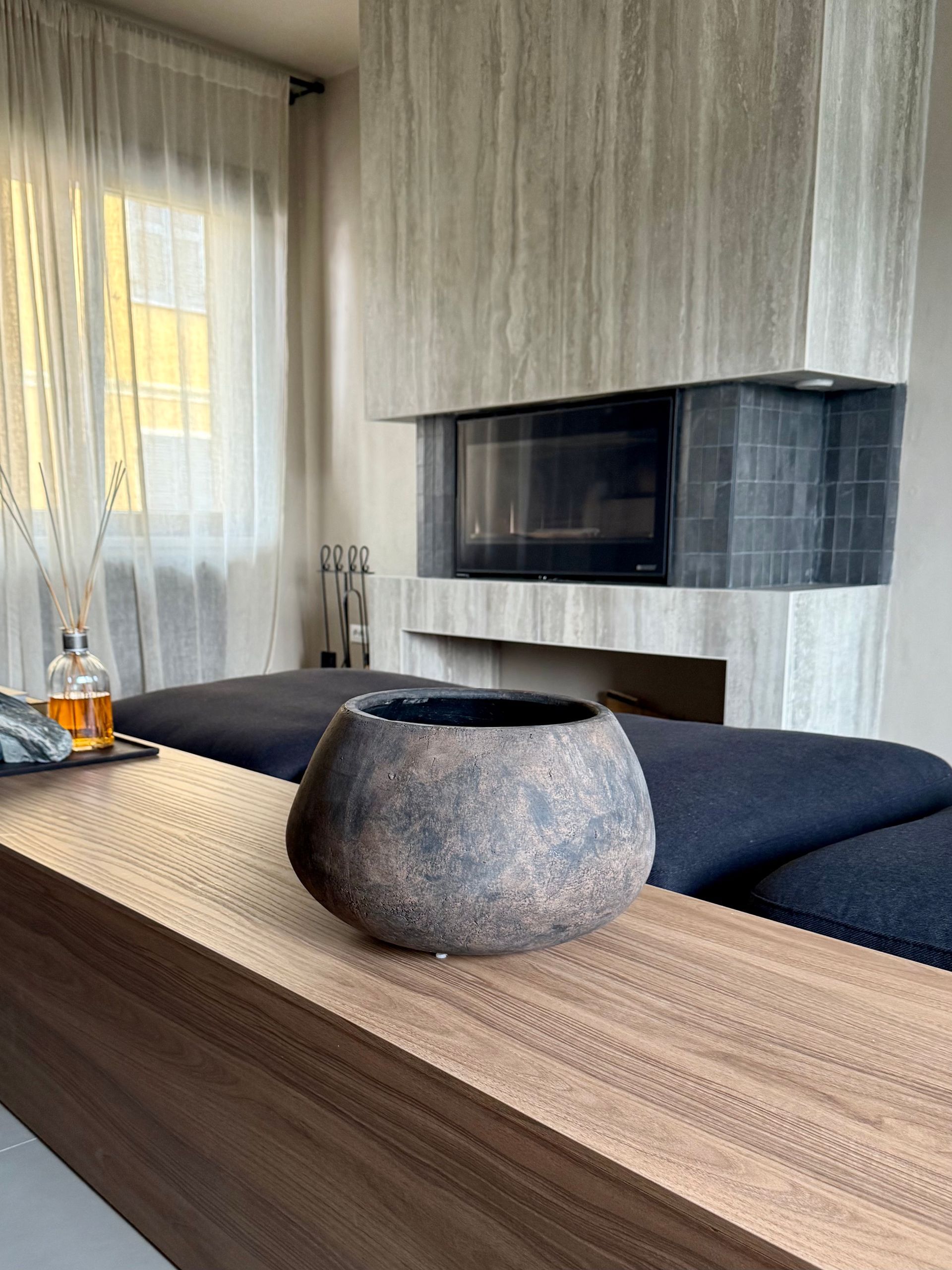 Exposed stone wall next to a hallway with an arched doorway and glass doors leading outside.