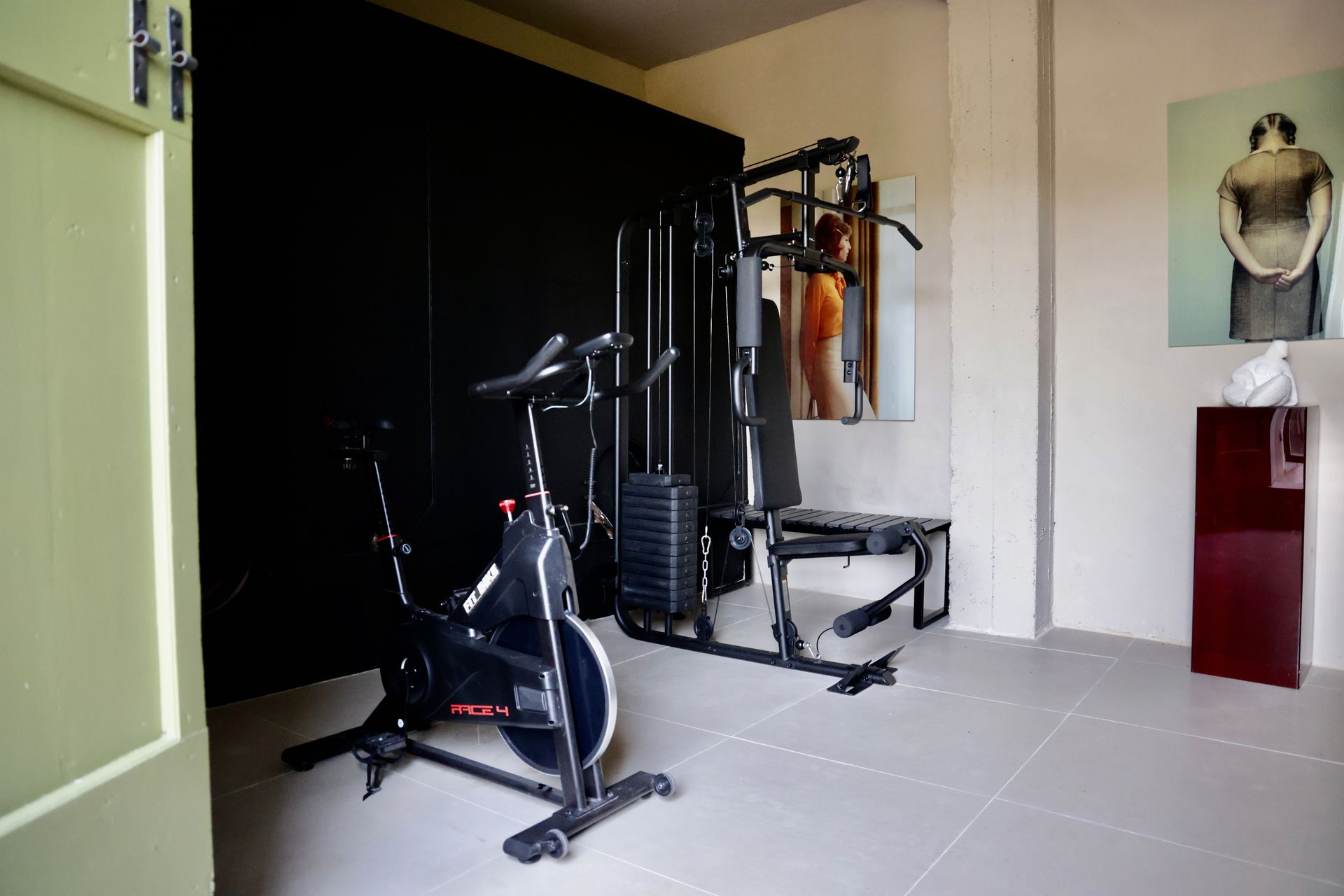 Home gym with exercise bike, weight machine, and artwork.