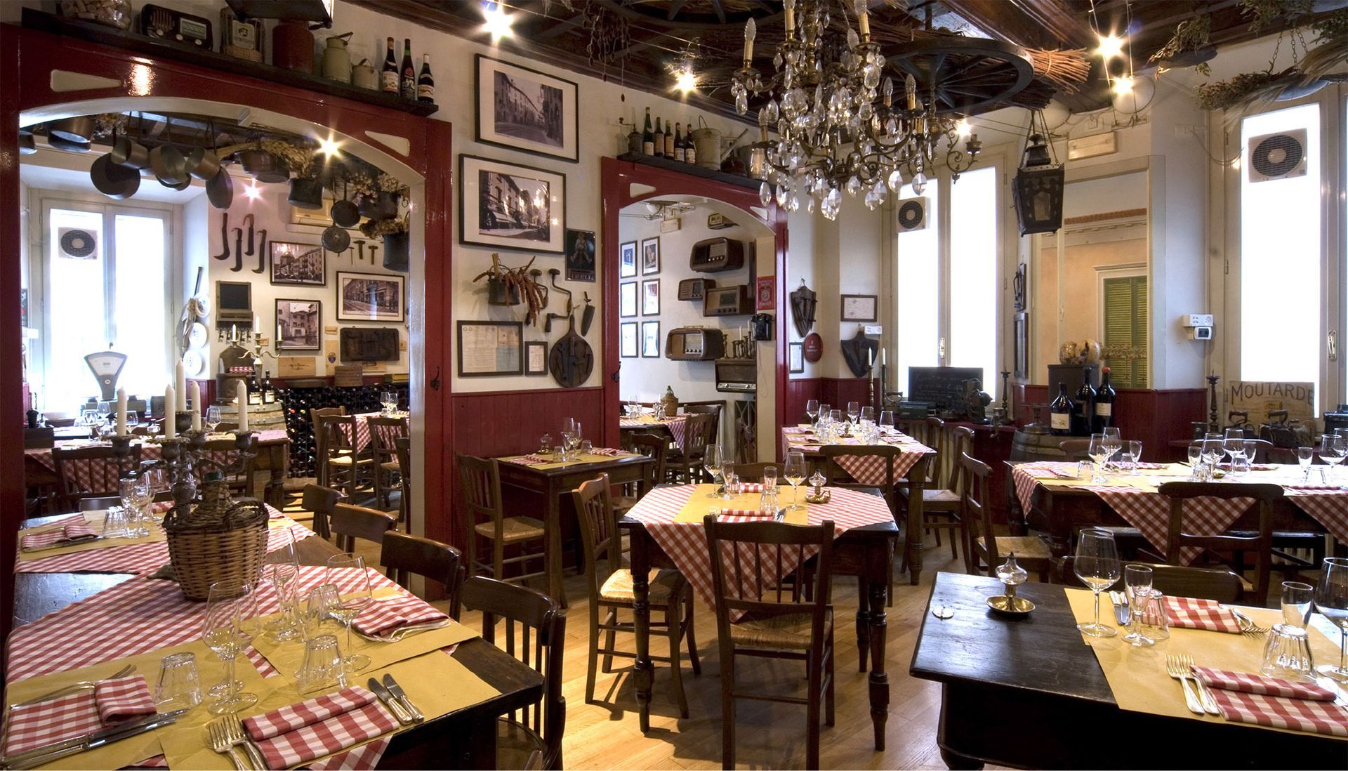 Restaurant interior with checkered tablecloths, tables set for diners, and ornate decor.
