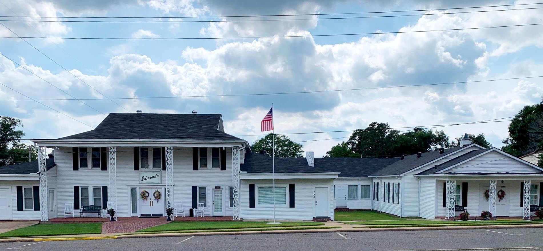 White church building with a steeple and American flag under a cloudy sky