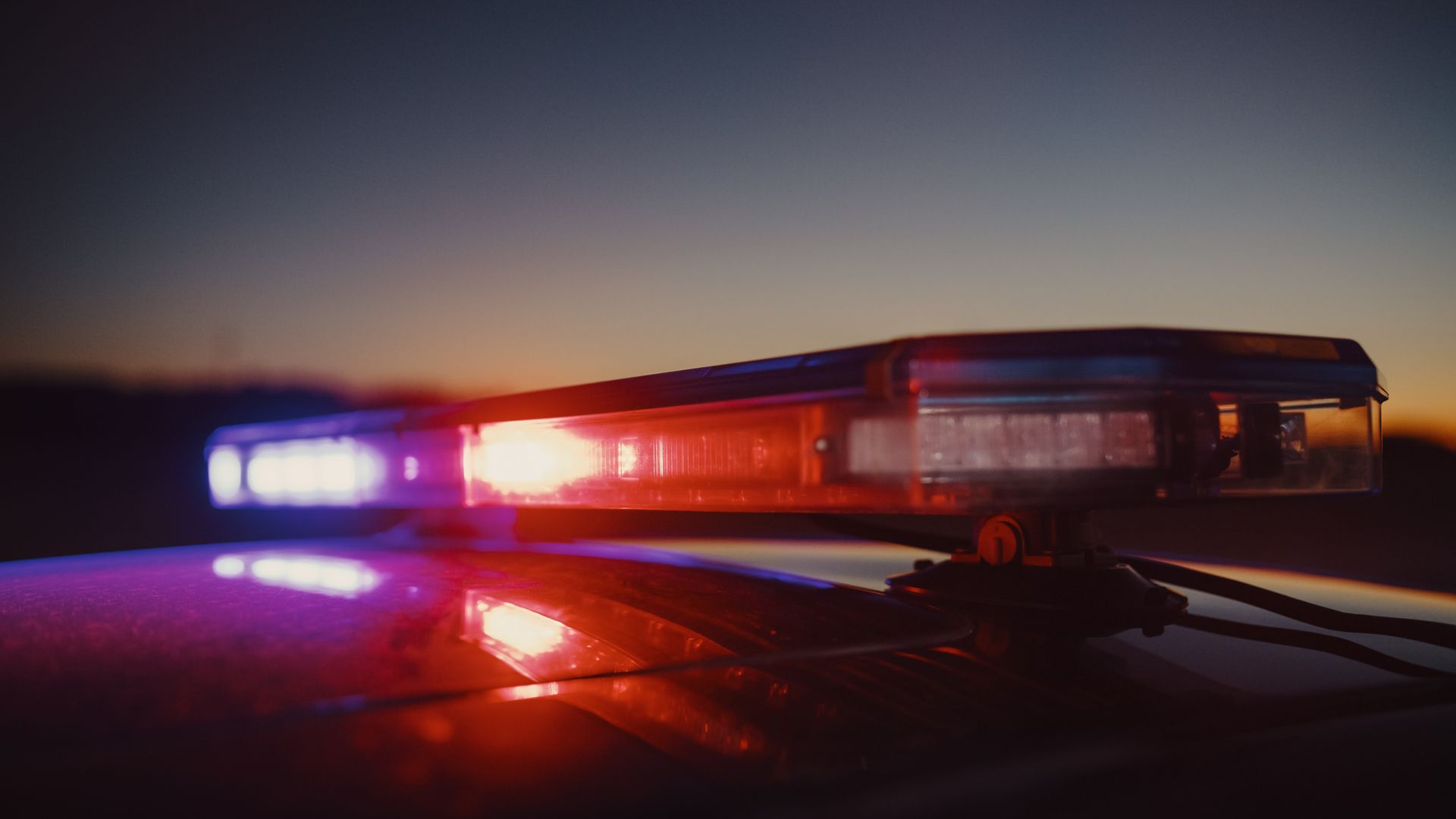 Inmate in orange jumpsuit sitting in jail cell, head in hands. A guard walks past.