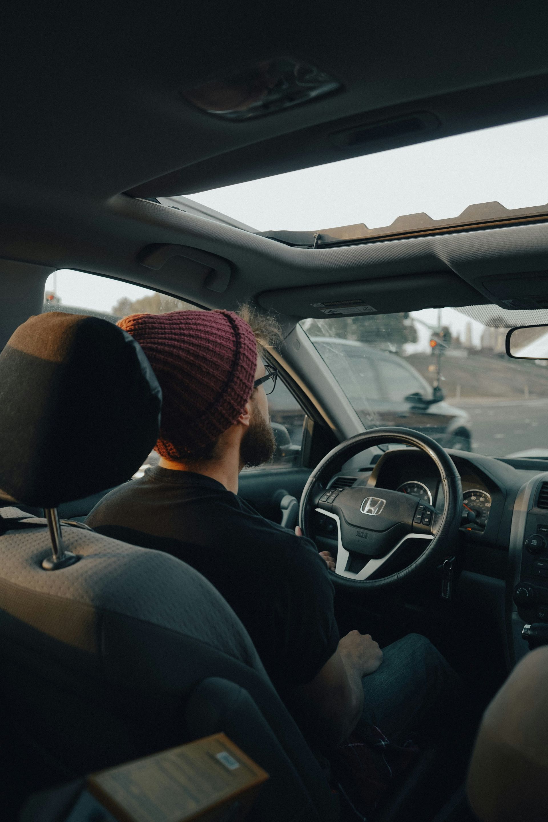 Side-view mirror of a moving car, reflecting scenery blurred by speed, earthy brown tones.