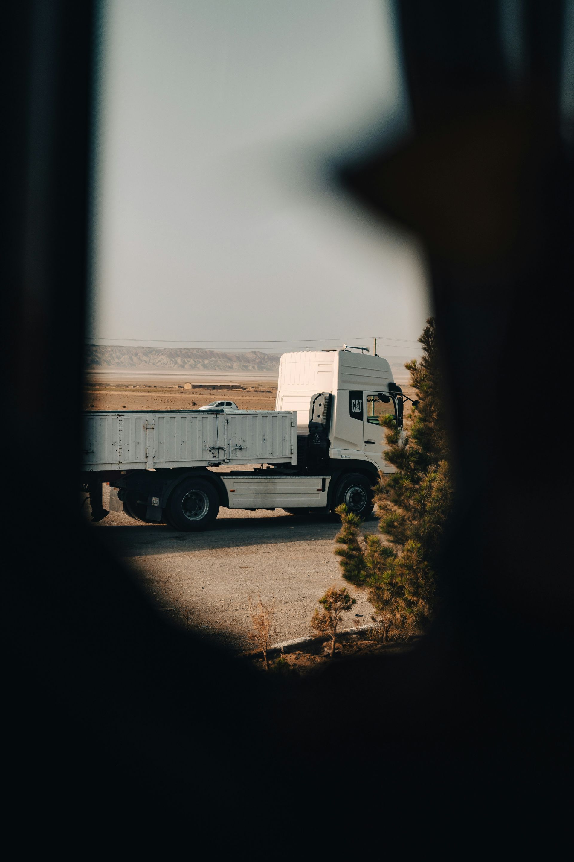 Side-view mirror of a moving car, reflecting scenery blurred by speed, earthy brown tones.