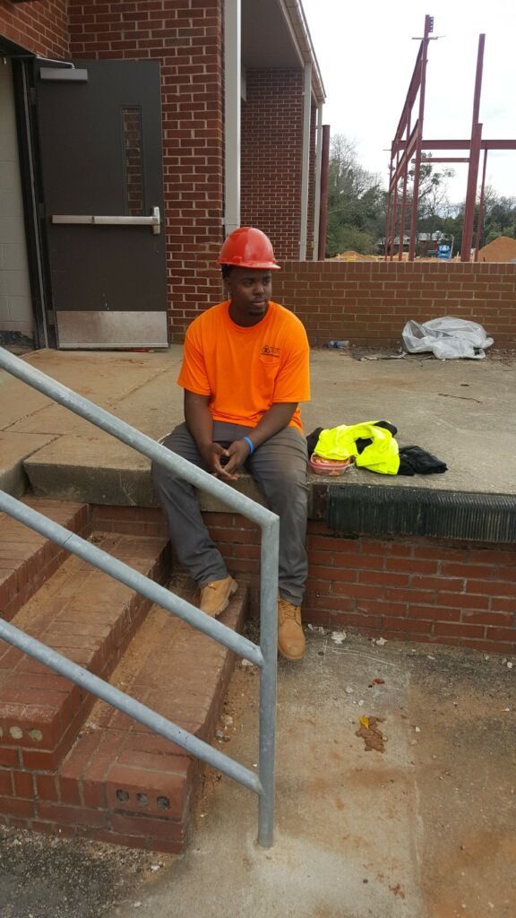 A man wearing a hard hat is sitting on a set of stairs.