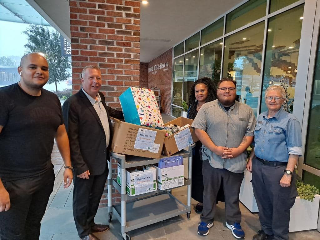 A group of people are standing in front of a cart filled with boxes.