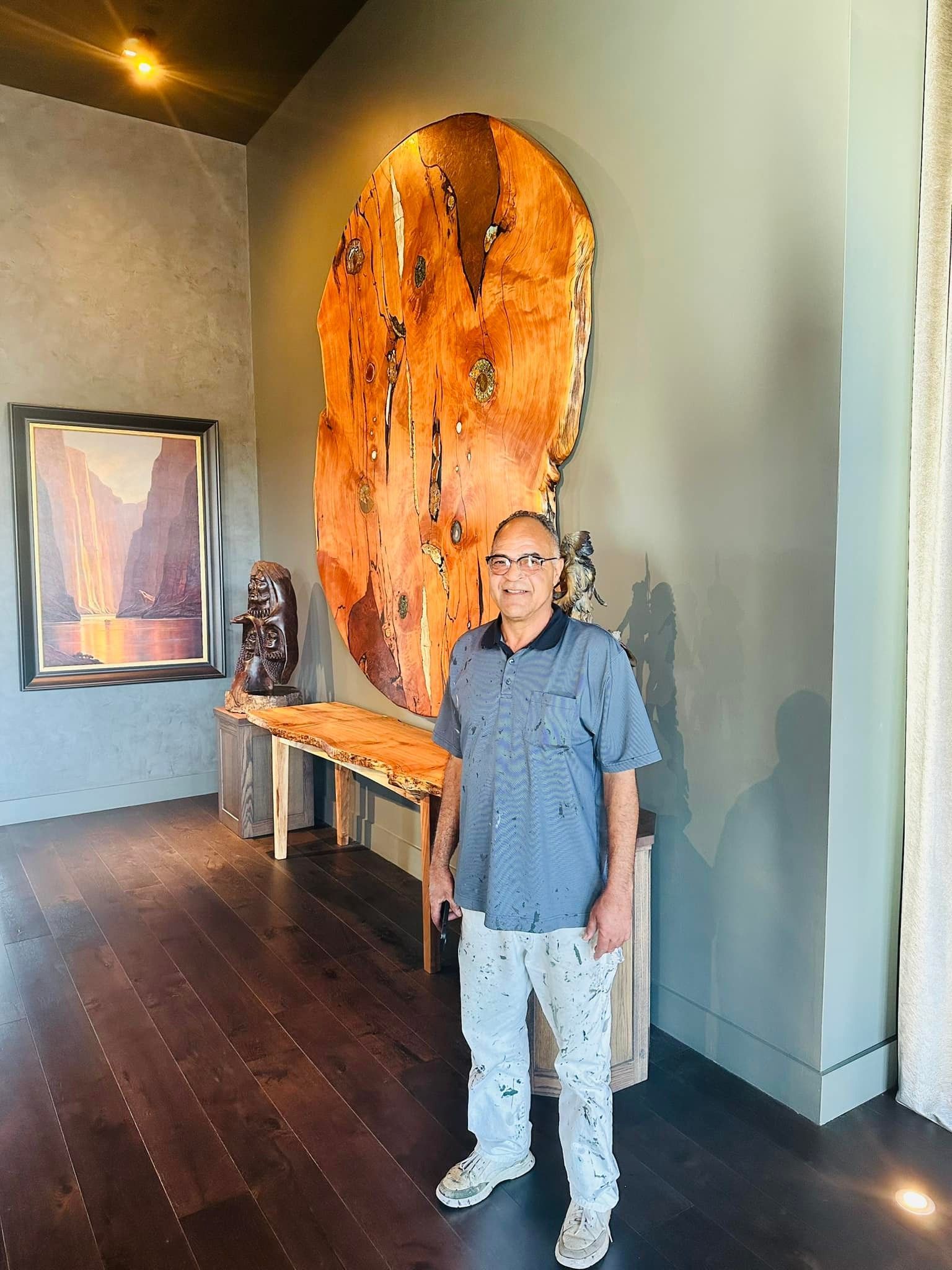 A man is standing in front of a large wooden sculpture in a room.