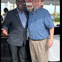 Two men are posing for a picture under a tent.