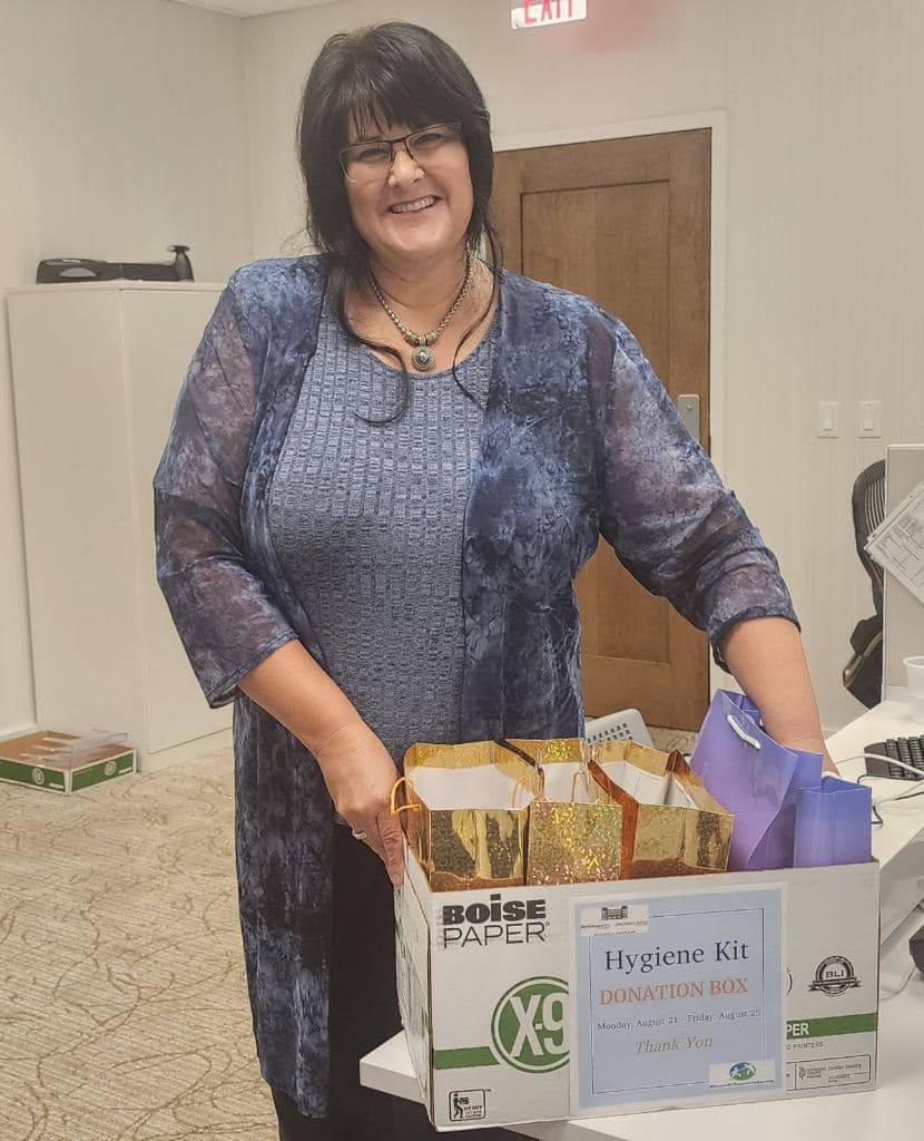 A woman in a blue dress is holding a box of food.