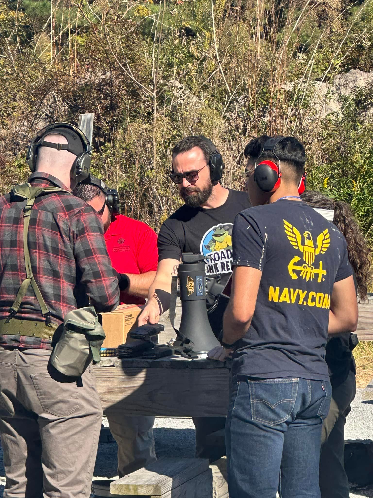 A group of men are standing around a table talking to each other.