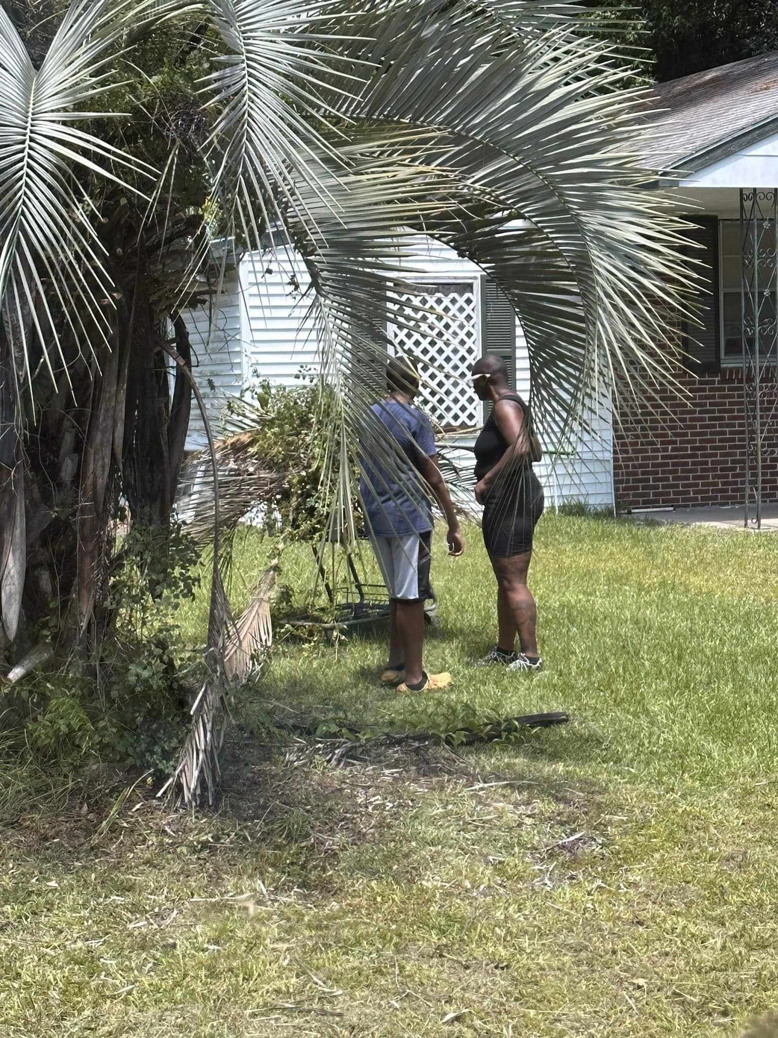 A man and a woman are standing in the grass in front of a house.