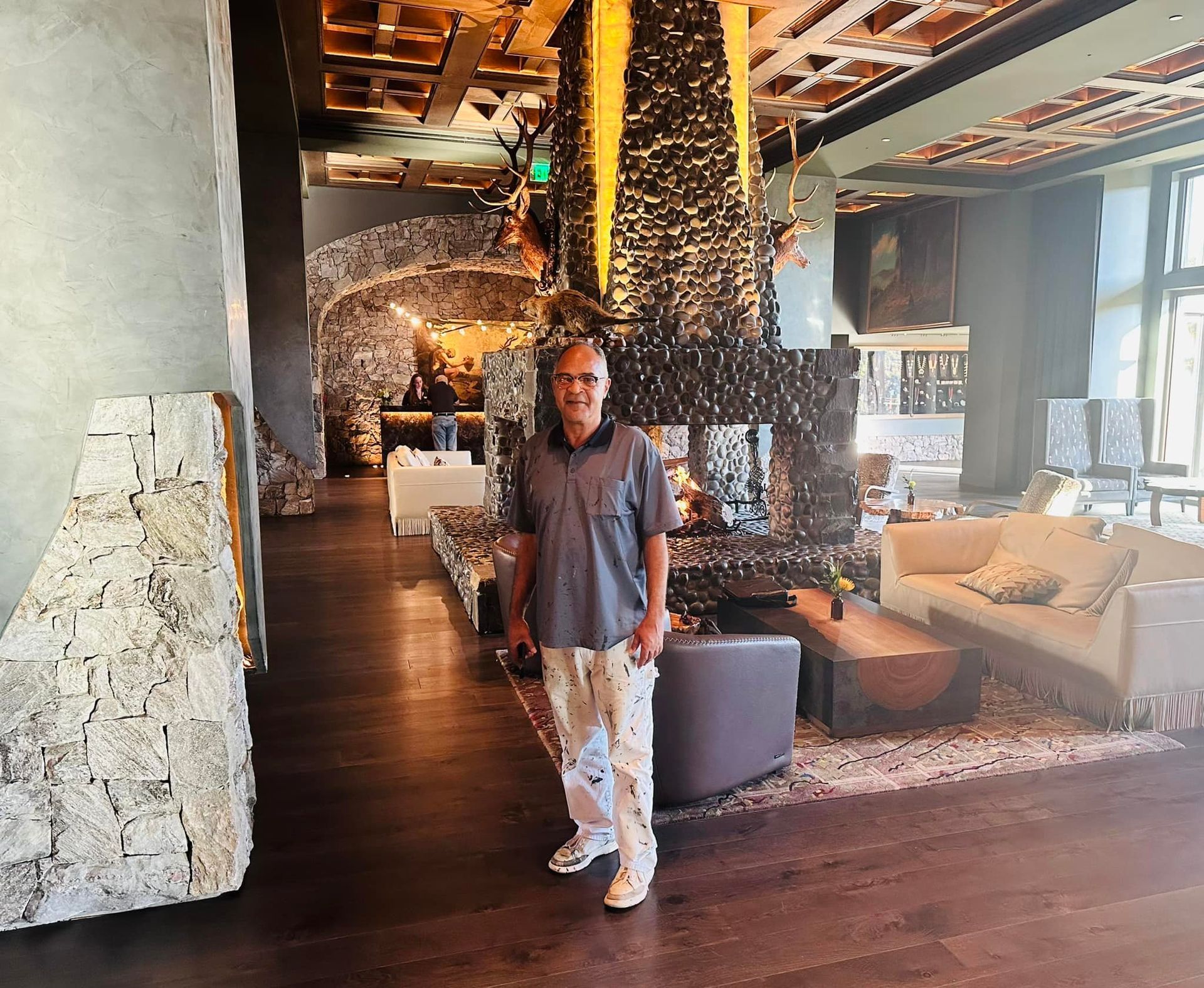 A man is standing in a living room in front of a fireplace.