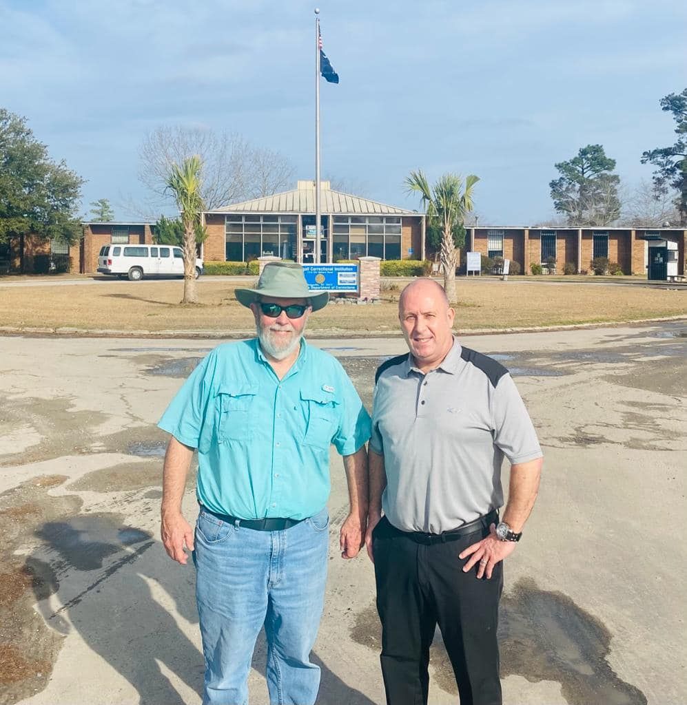 Two men are posing for a picture in front of a building