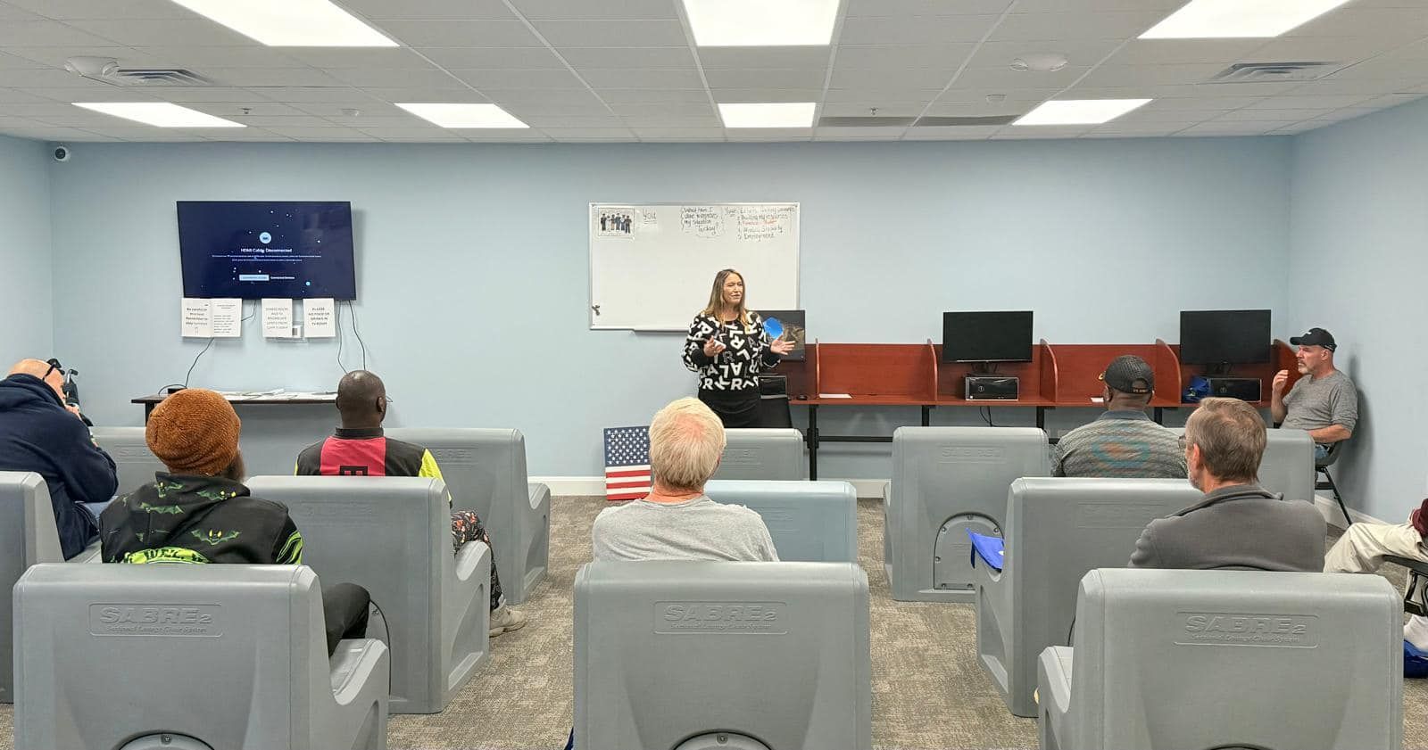 A woman is giving a presentation to a group of people in a classroom.