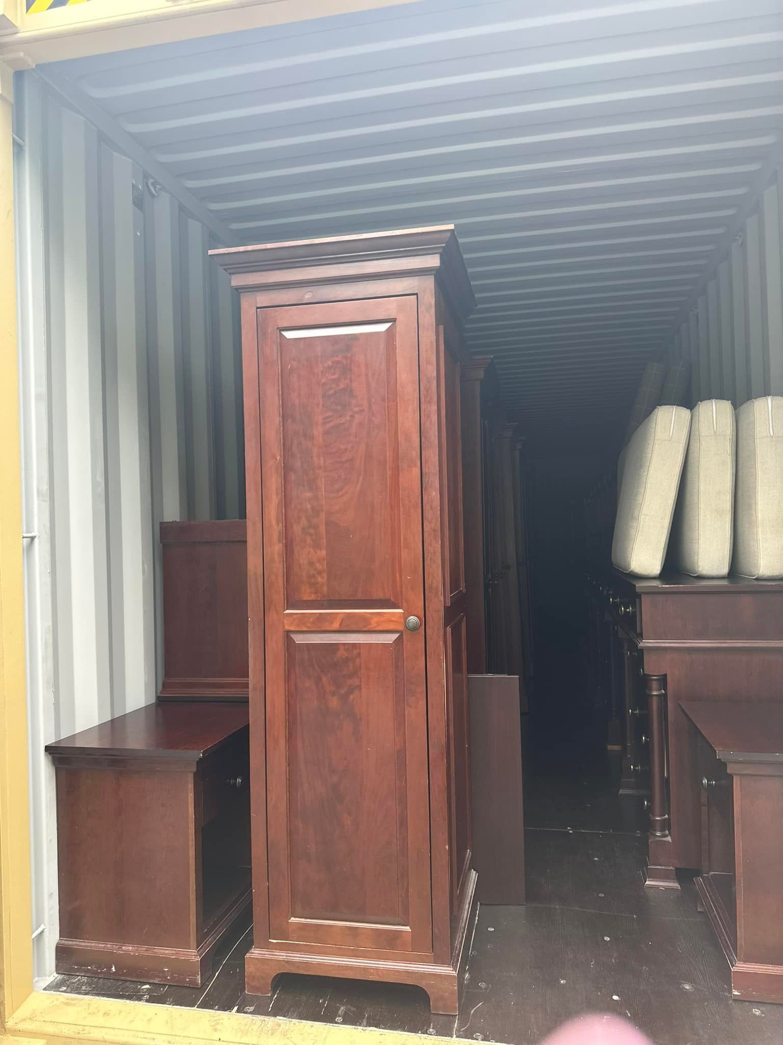 A container filled with wooden furniture and mattresses.