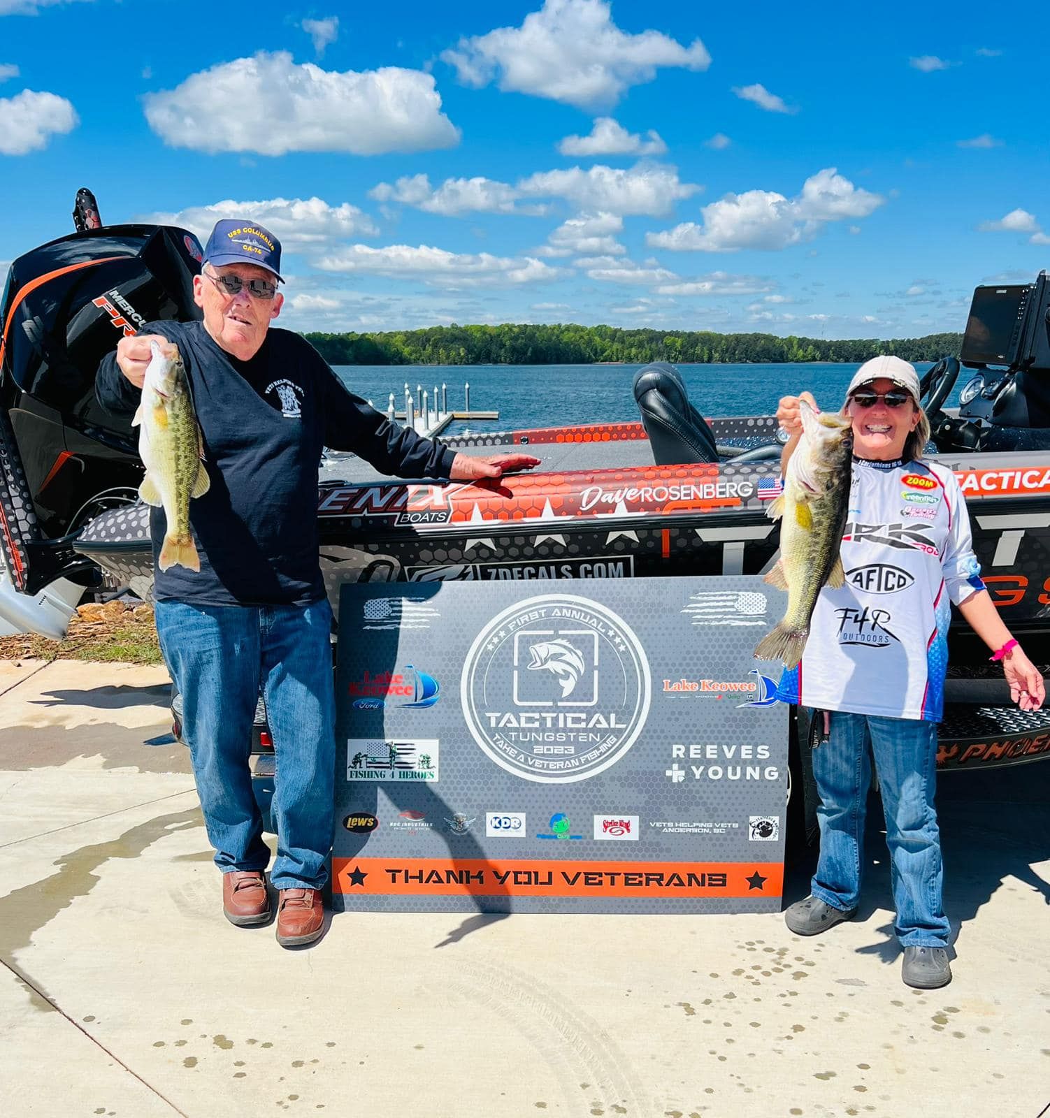 A man and a boy are holding fish in front of a boat.