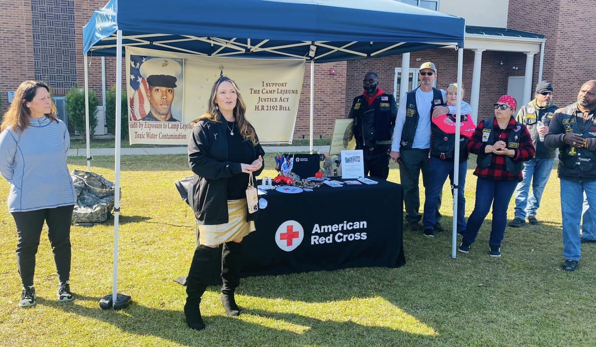 A group of people are standing around a table under a tent.