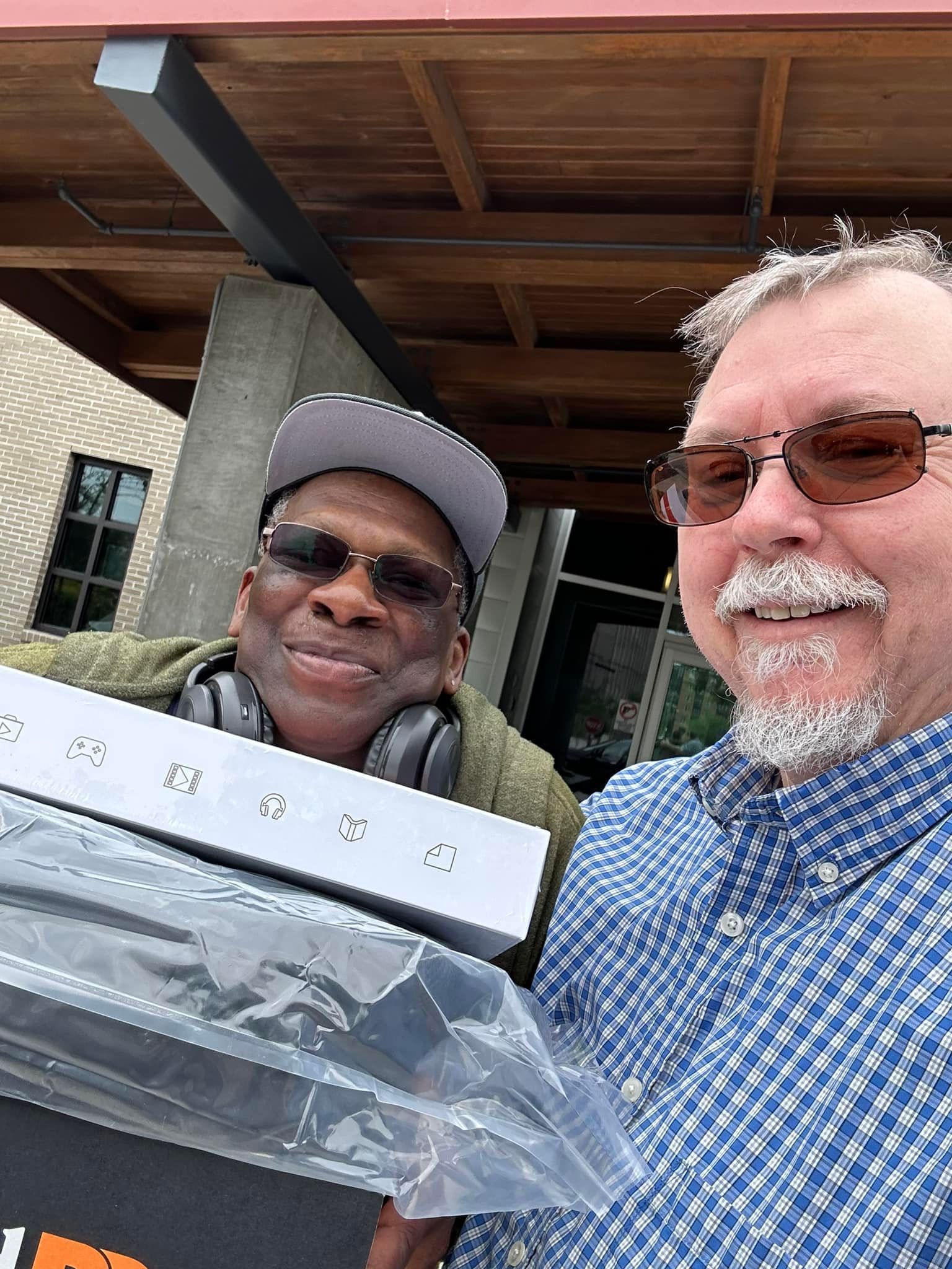 Two men are standing next to each other holding a box.
