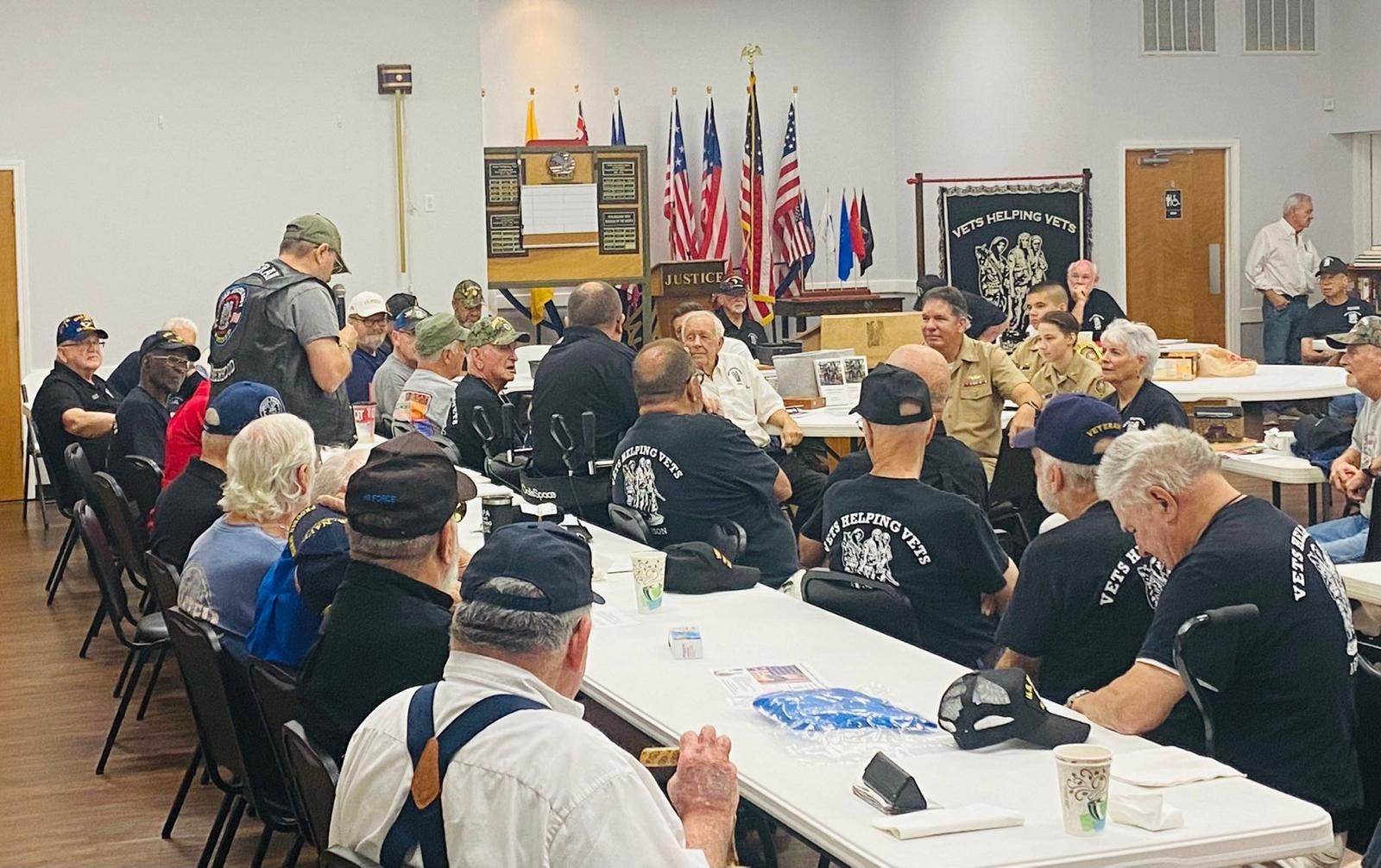 A large group of people are sitting at tables in a room.