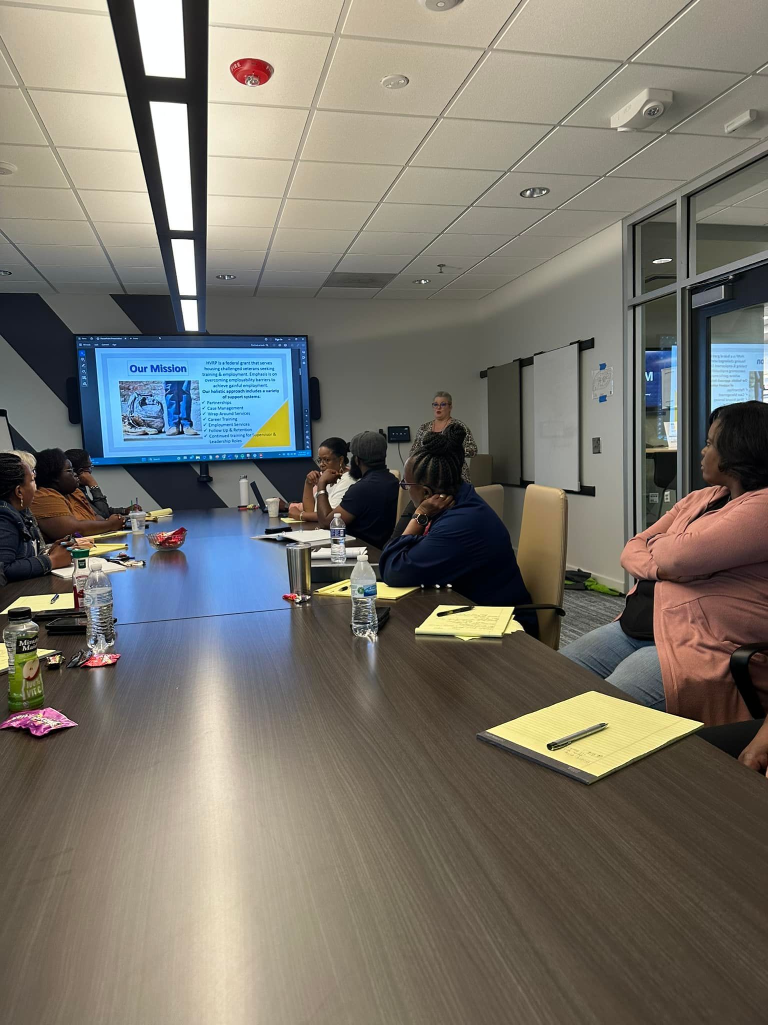 A group of people are sitting at a long table in a conference room.