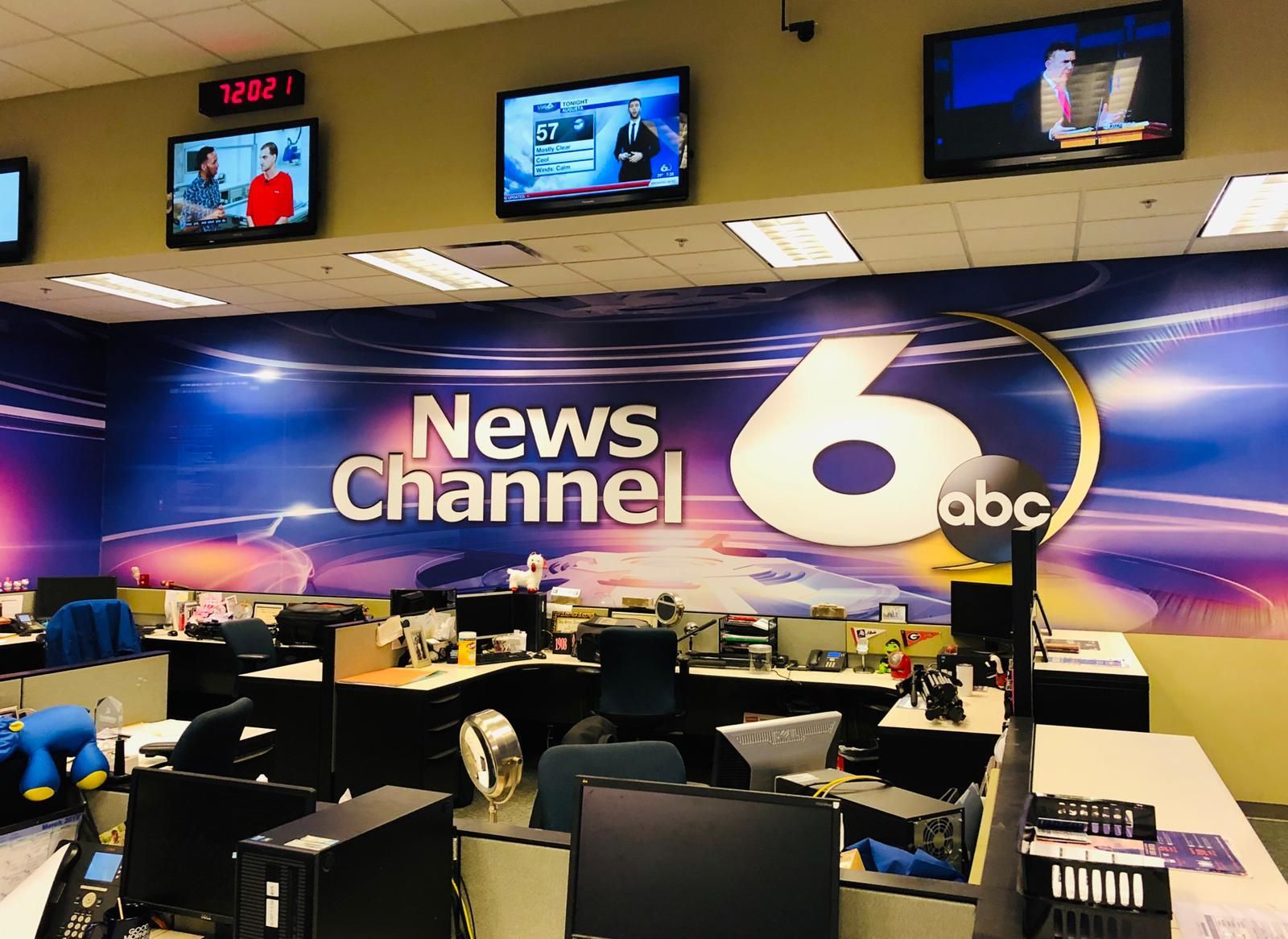 A news channel 6 office with many monitors on the wall