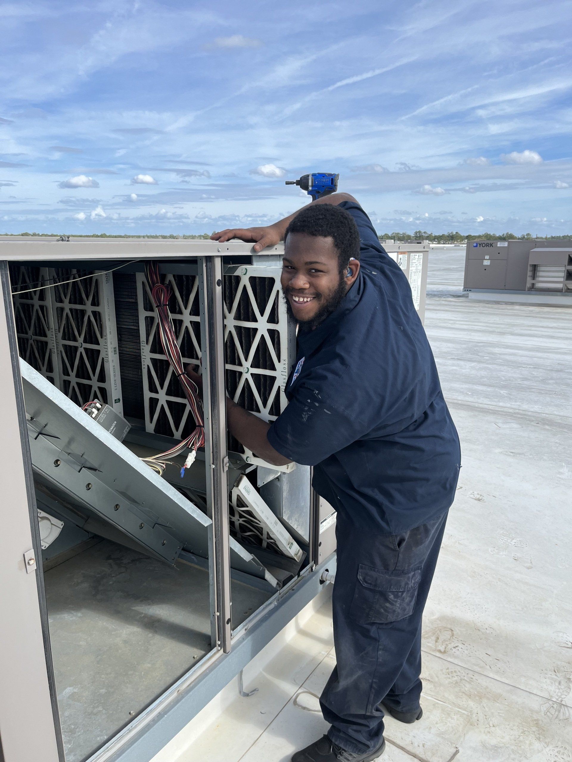 A man is working on an air conditioner on a roof.