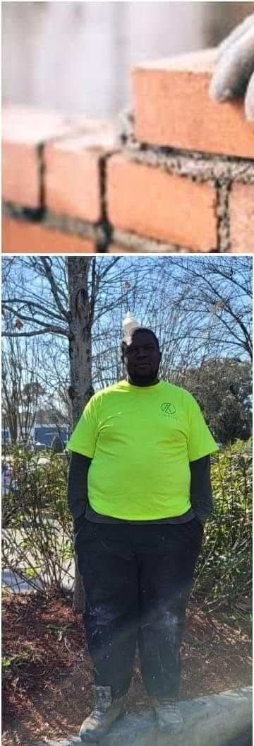 A man in a neon yellow shirt is standing in front of a brick wall.
