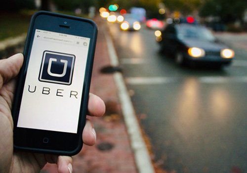 A person is holding a cell phone with the uber logo on it.