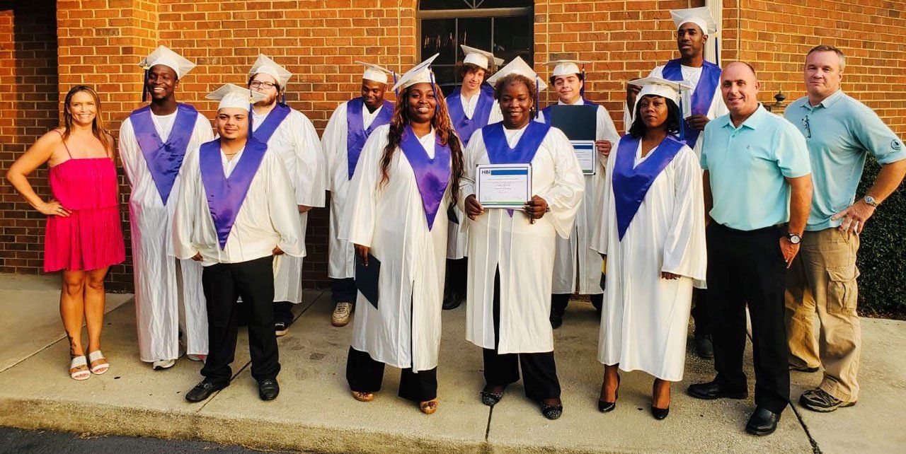 A group of graduates are posing for a picture in front of a brick building.
