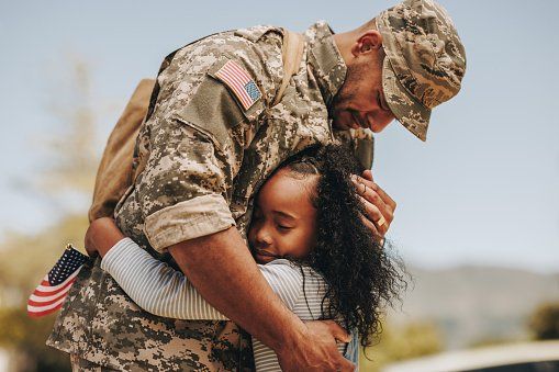 A soldier is hugging a little girl.